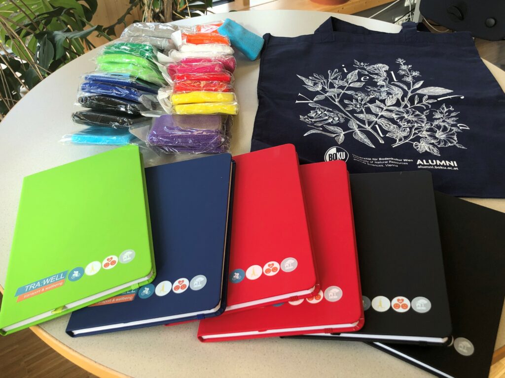 Auf einem Tisch werden Goodies für die Schüler präsentiert: Notizbücher, Taschen, Schweißband